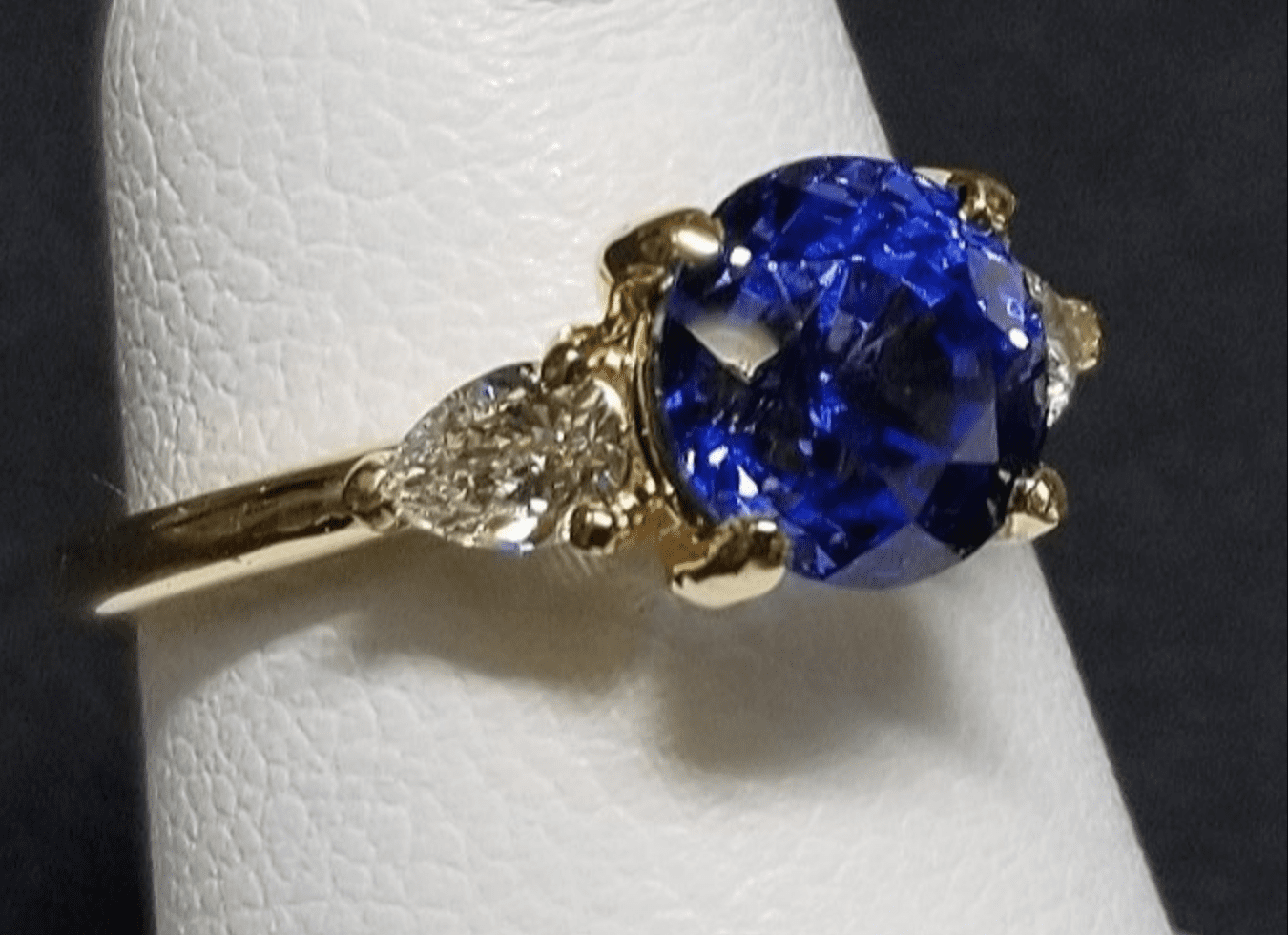 A gold ring with a large blue gemstone flanked by two smaller clear diamonds